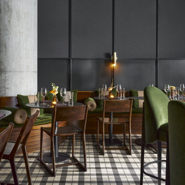Moody and elegant dining room at the Garden & Gun Club featuring lush green soft goods and dark wooden furniture.